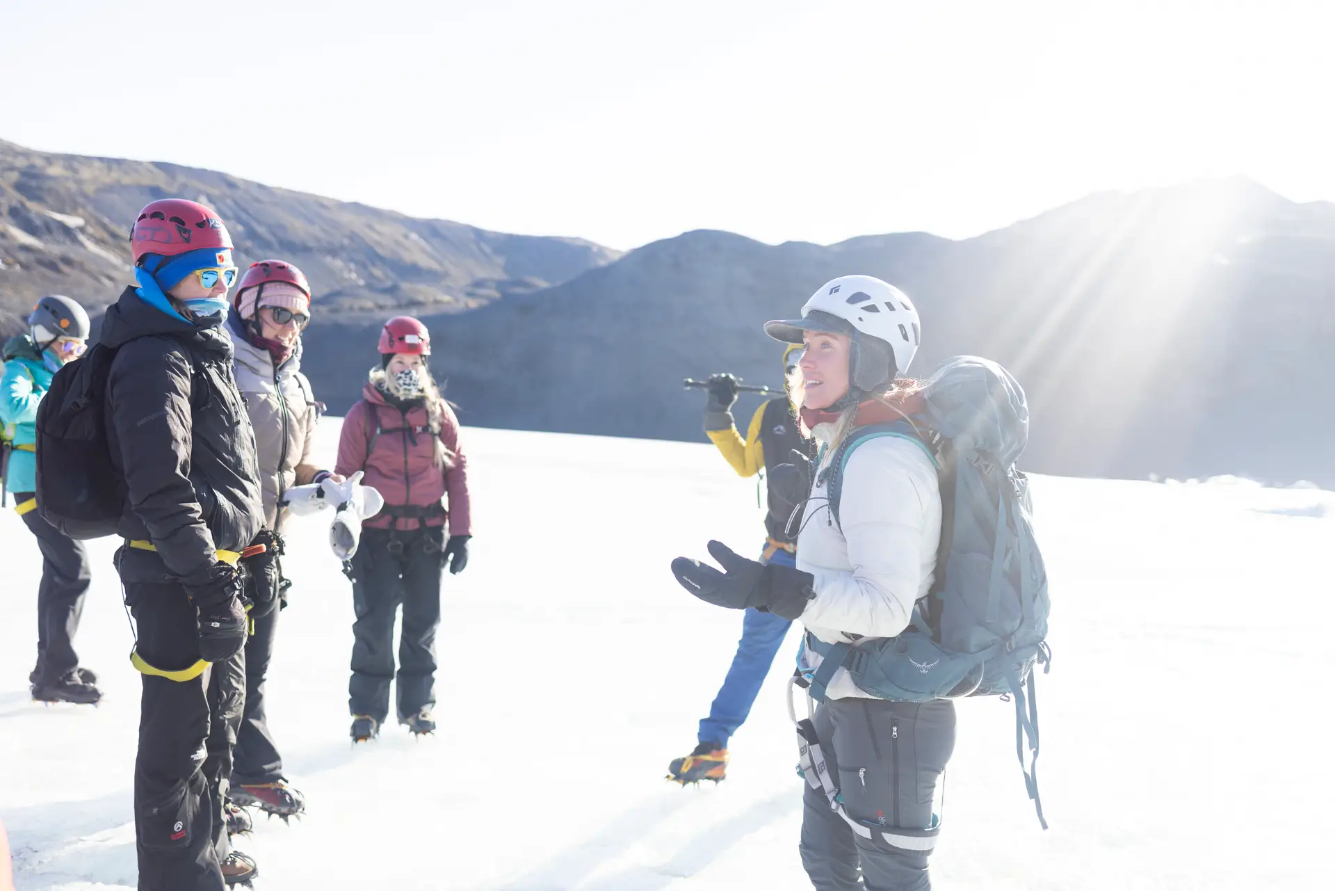 Women in helmets and crampons on a sunny glacier