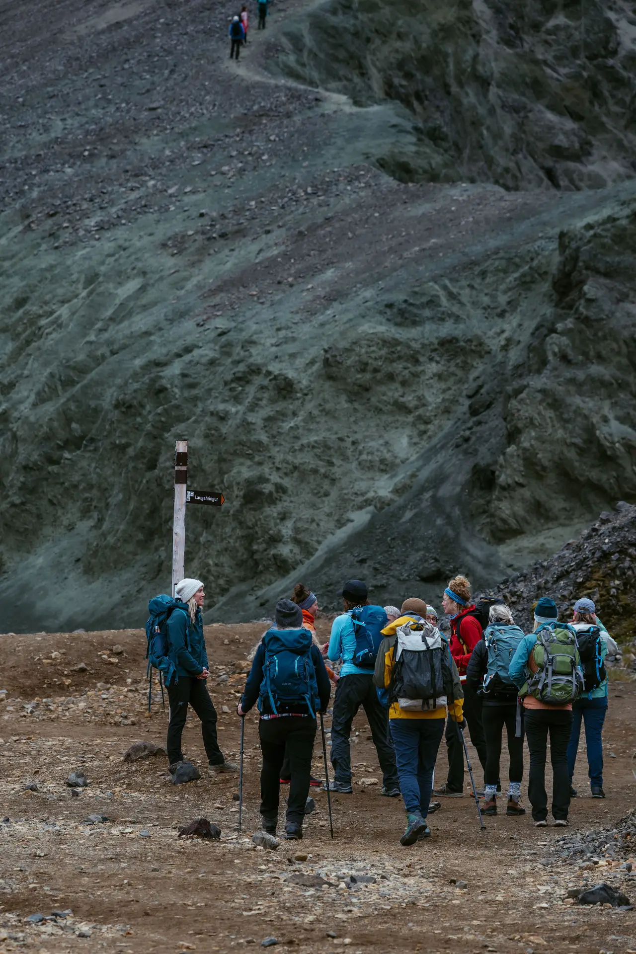 Group of hikers at the foot of a steep mossy slope