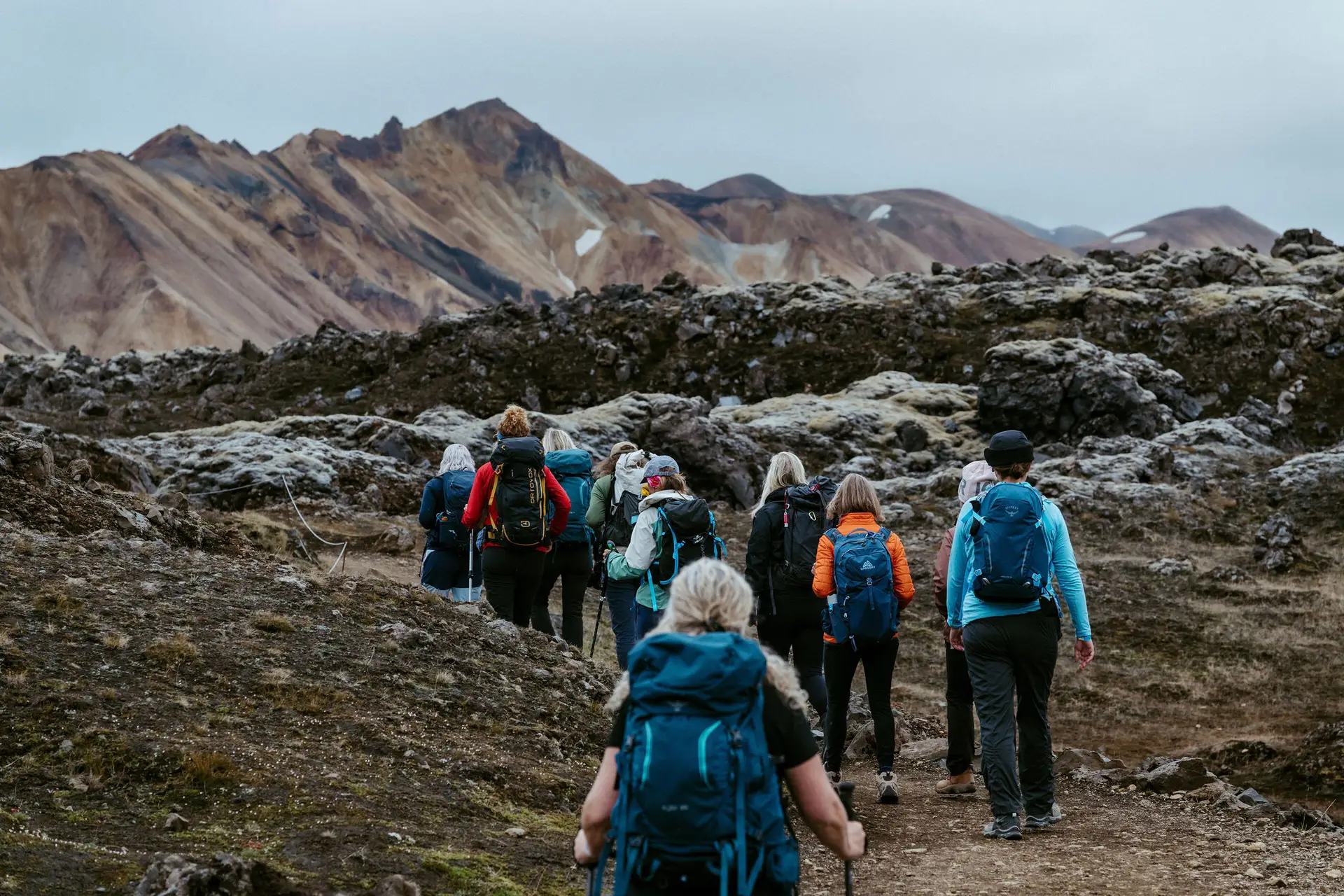 Hikers with backpacks walking toward colorful rhyolite mountains