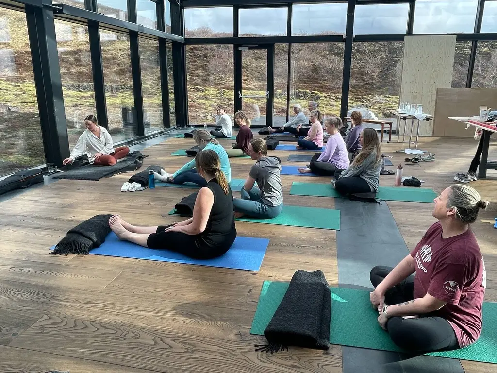 Women doing yoga on mats in a glass-walled room