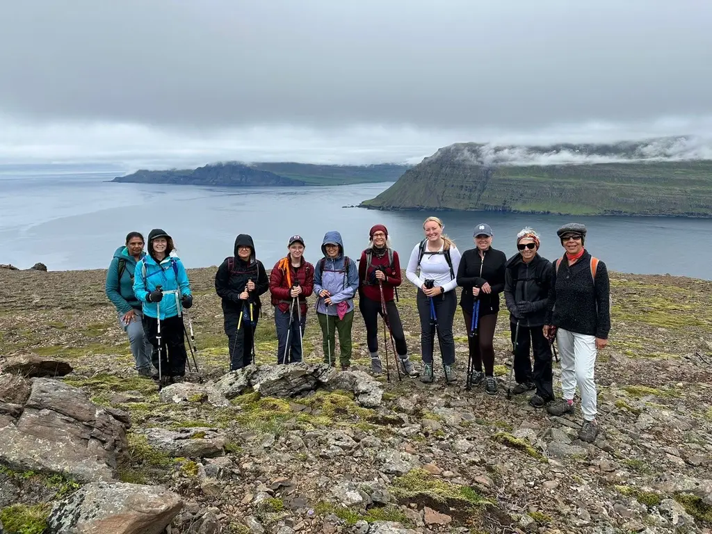 Group of hikers on a rocky headland above a fjord