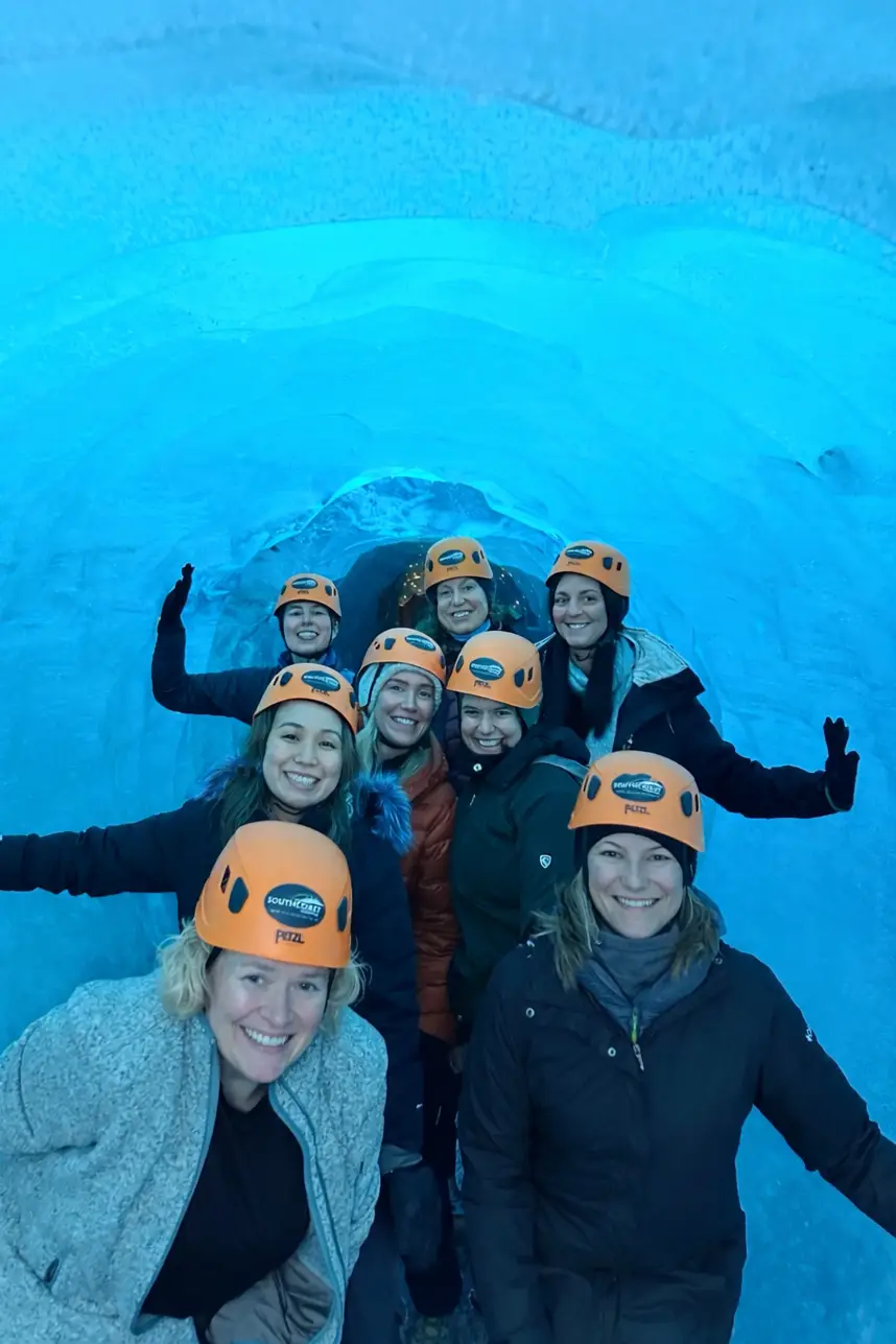 Group in orange helmets inside a blue ice cave