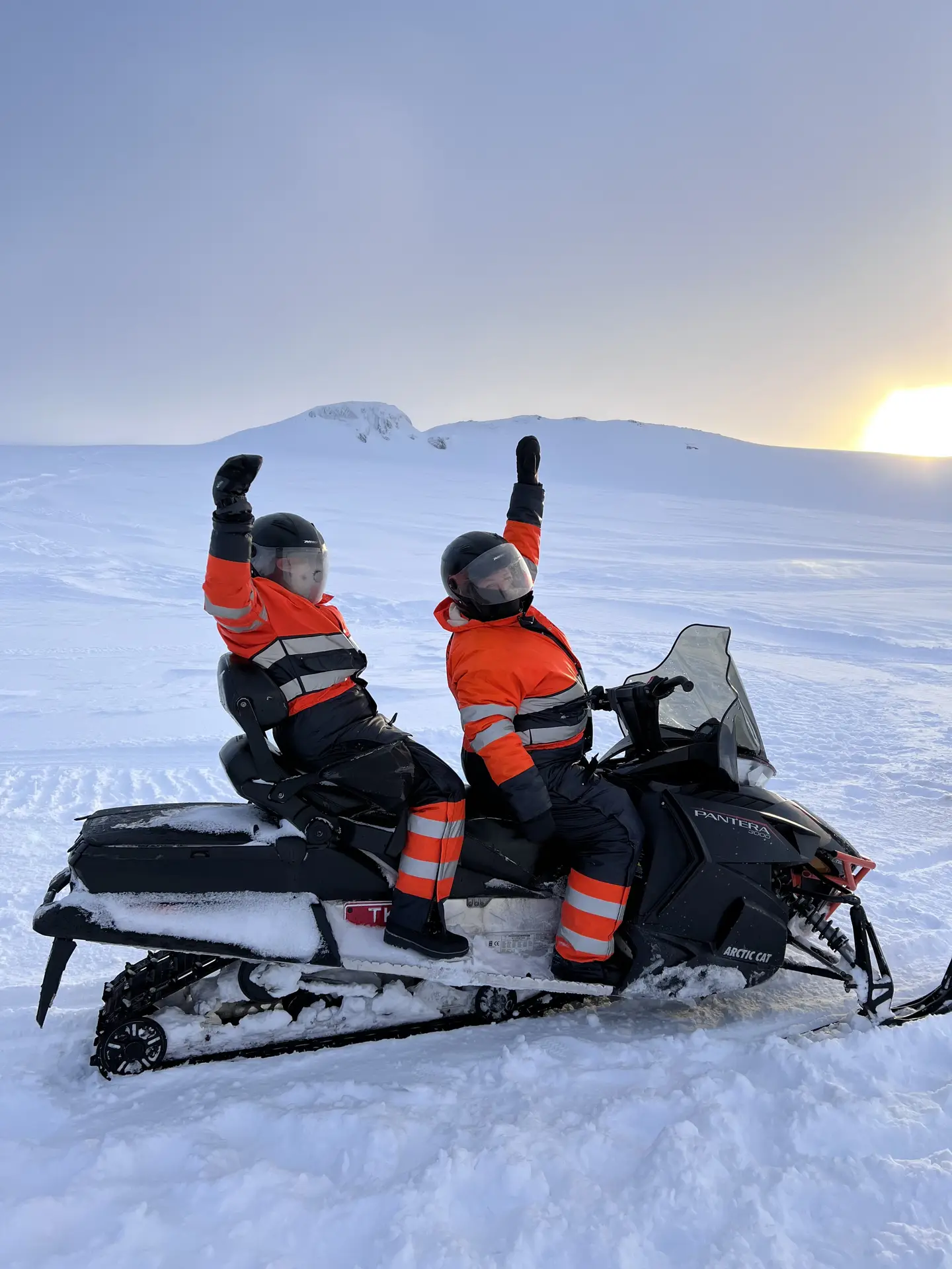 Two people on a snowmobile cheering