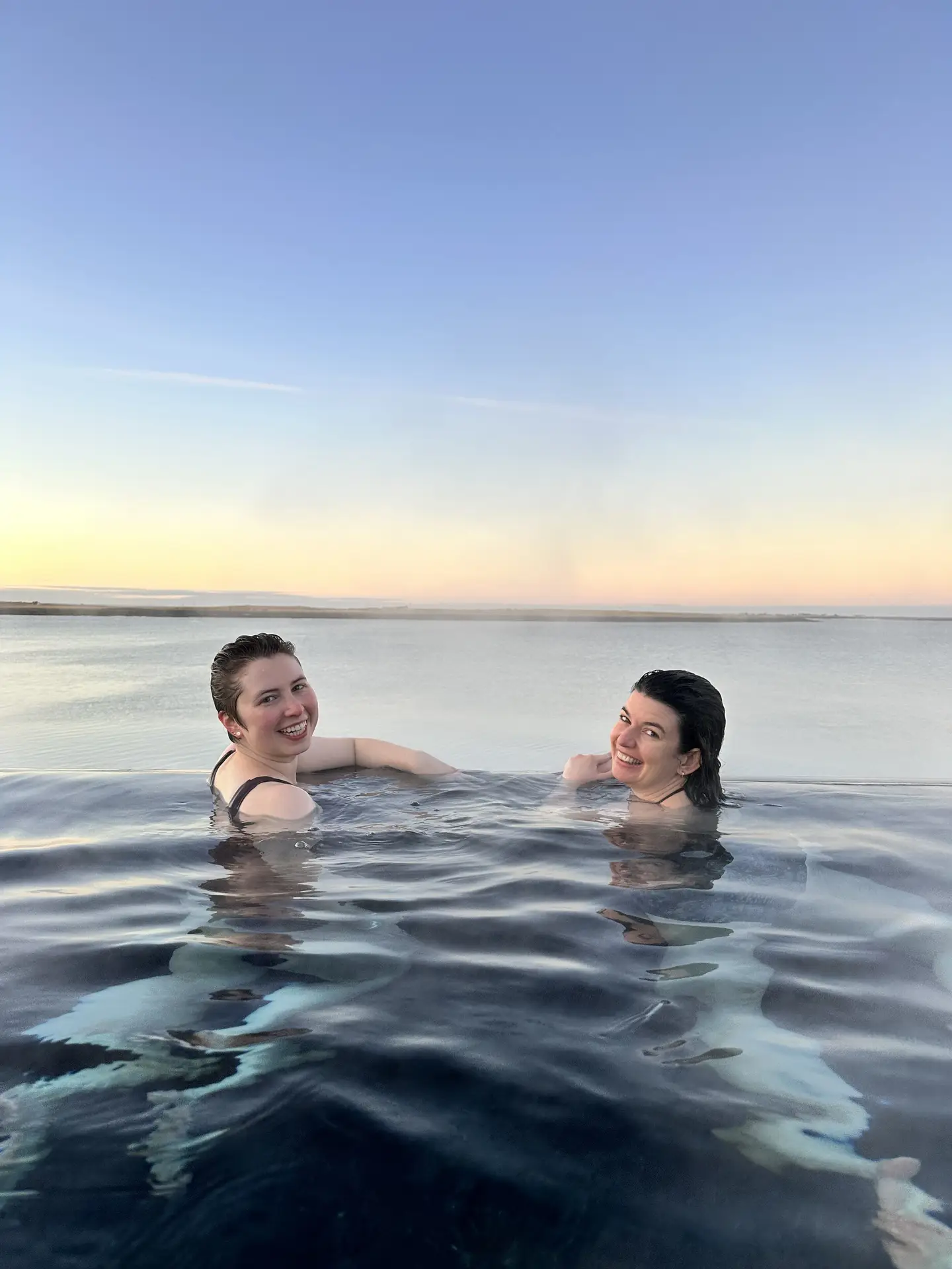 Two women relaxing in a pool at dusk