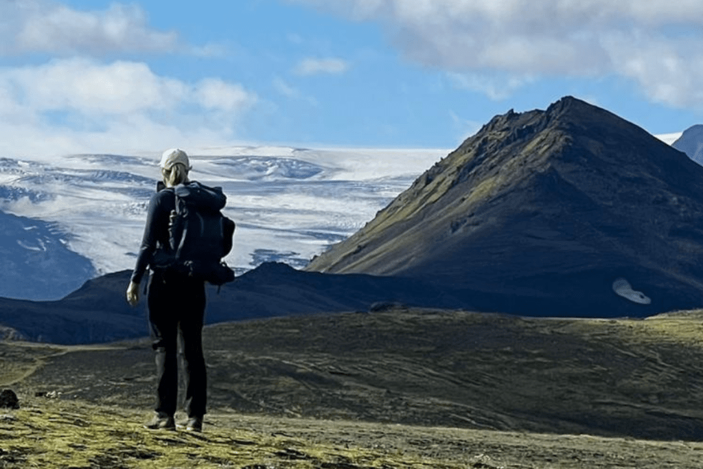 Hiker with a backpack looking toward snow-capped mountains