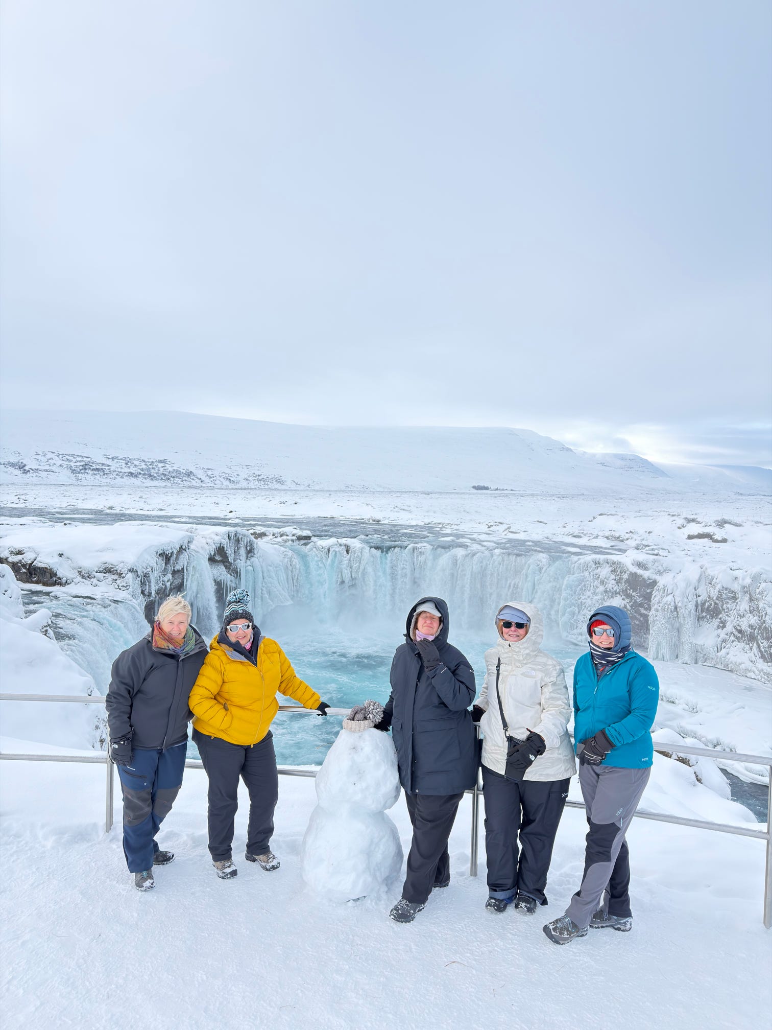 Women posing in front of a frozen waterfall in winter