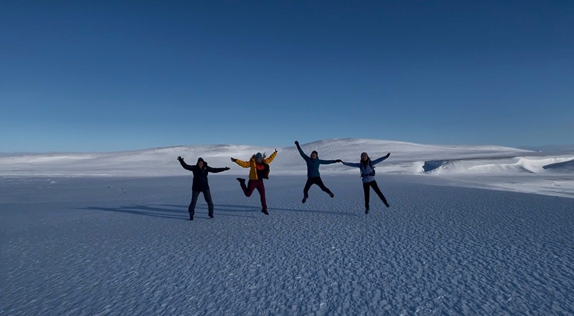 Four people jumping on a vast snowfield