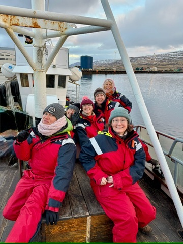 Women in red flotation suits on a boat