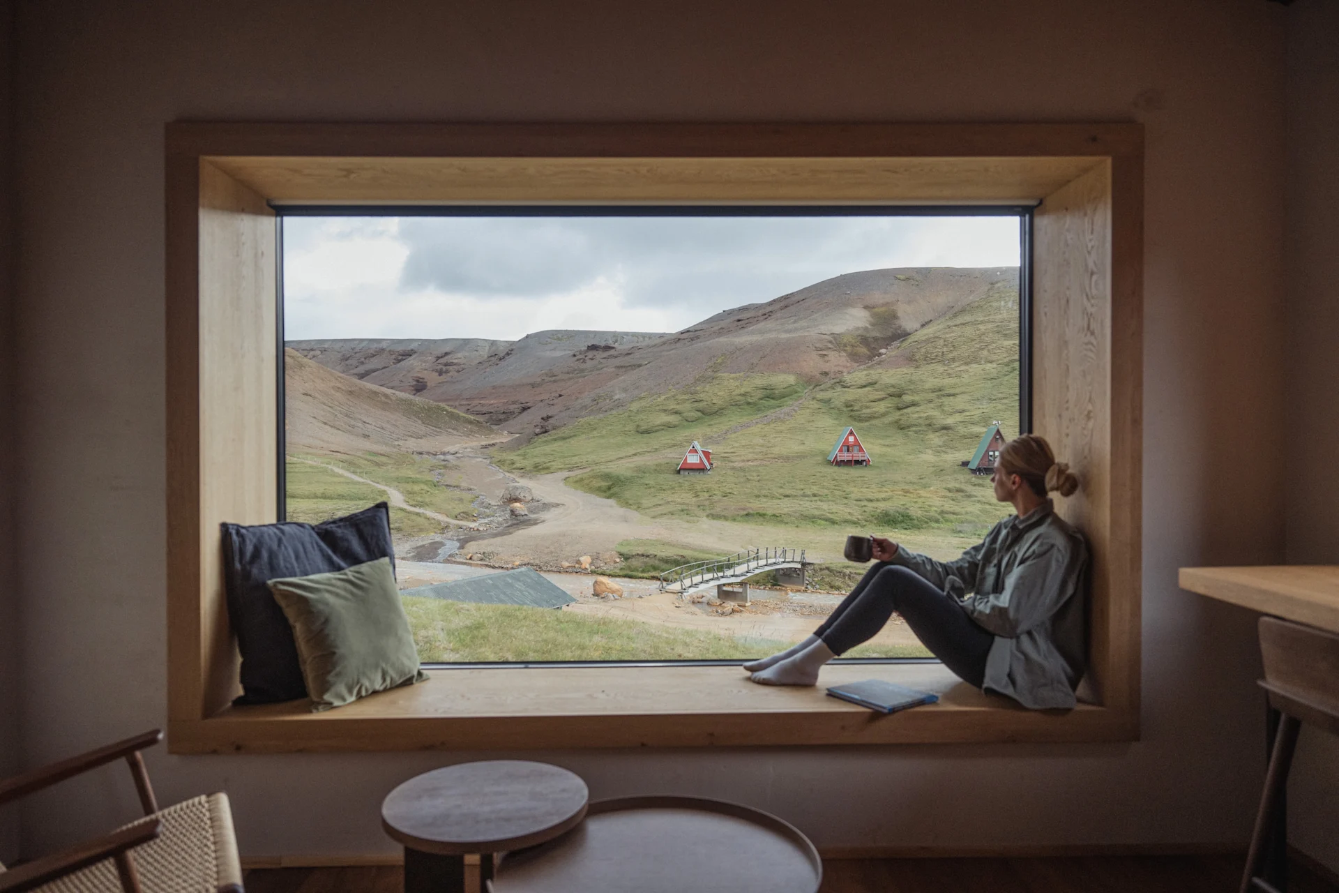 Woman relaxing in a window seat overlooking green hills