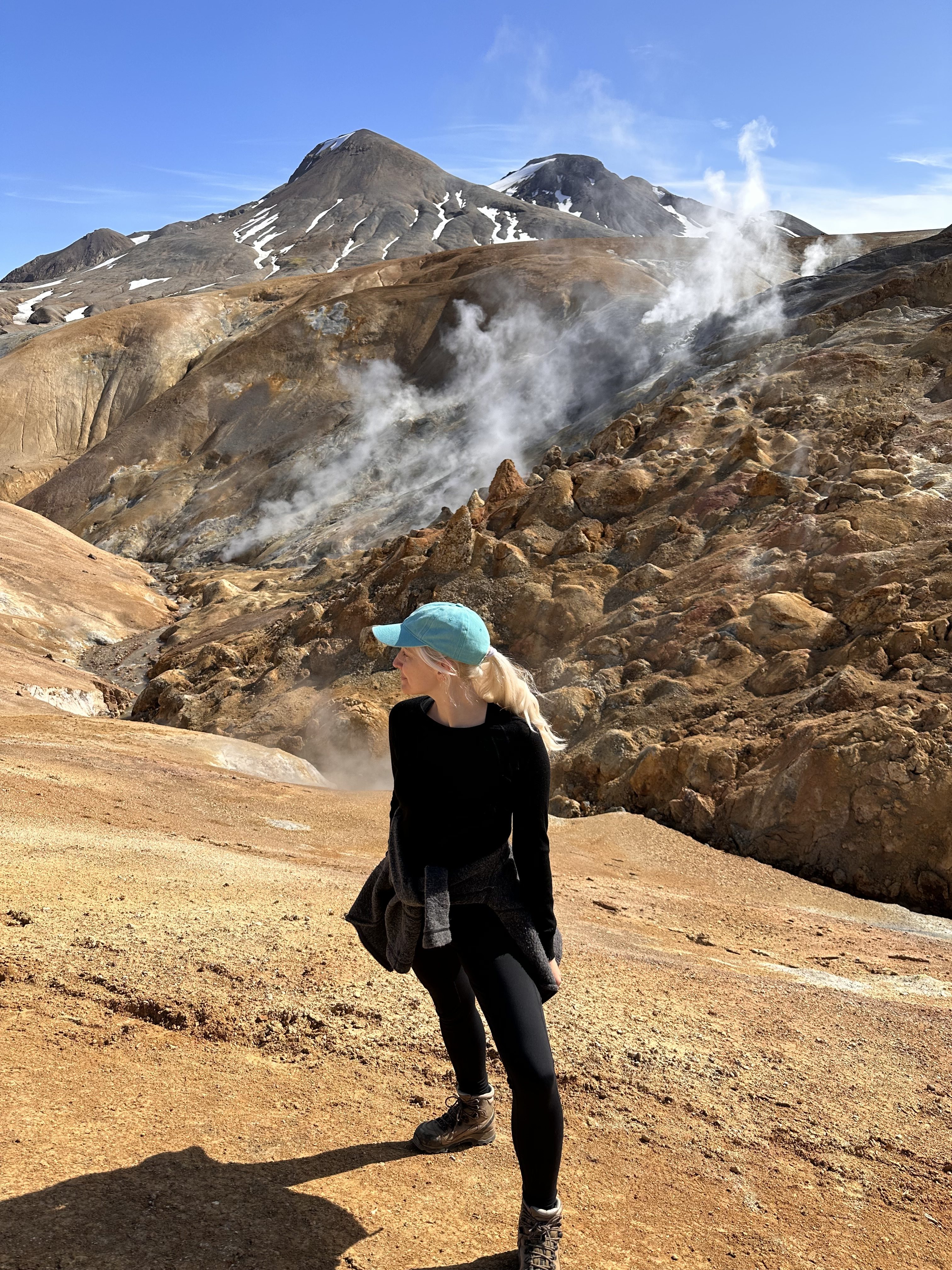 Woman standing among steaming geothermal vents