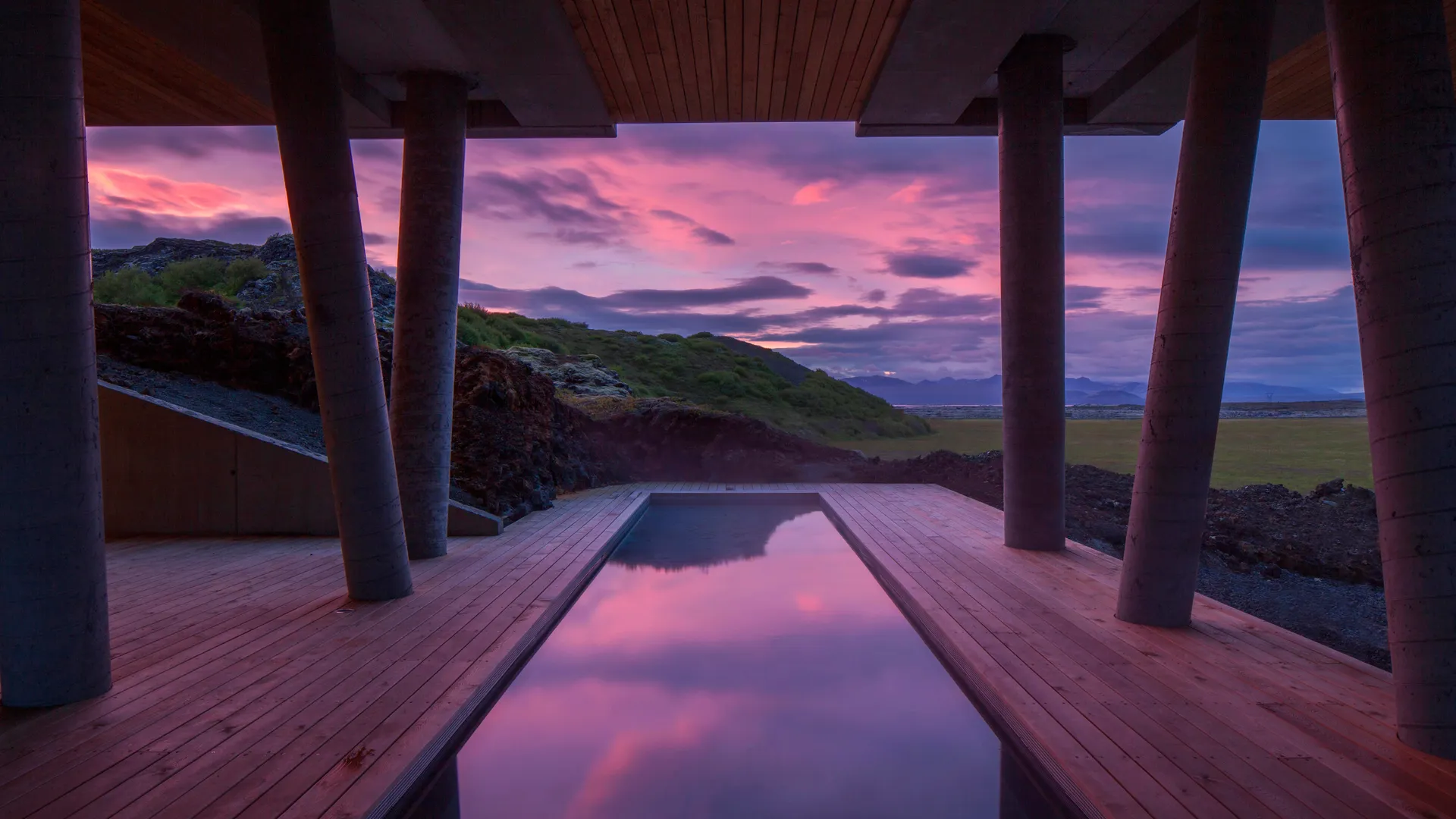 Outdoor pool reflecting a pink sunset sky