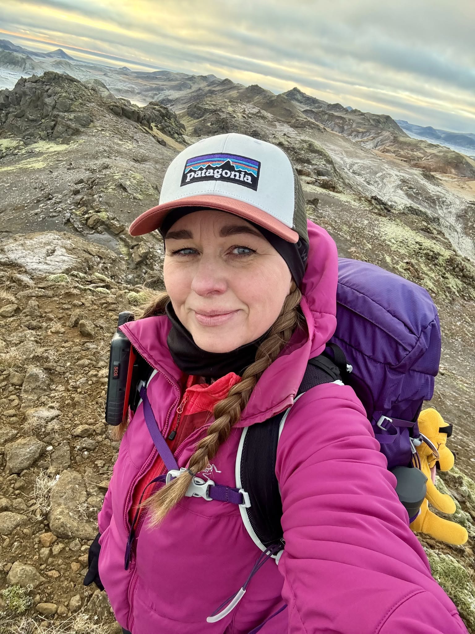 Smiling woman hiker in a cap and pink jacket