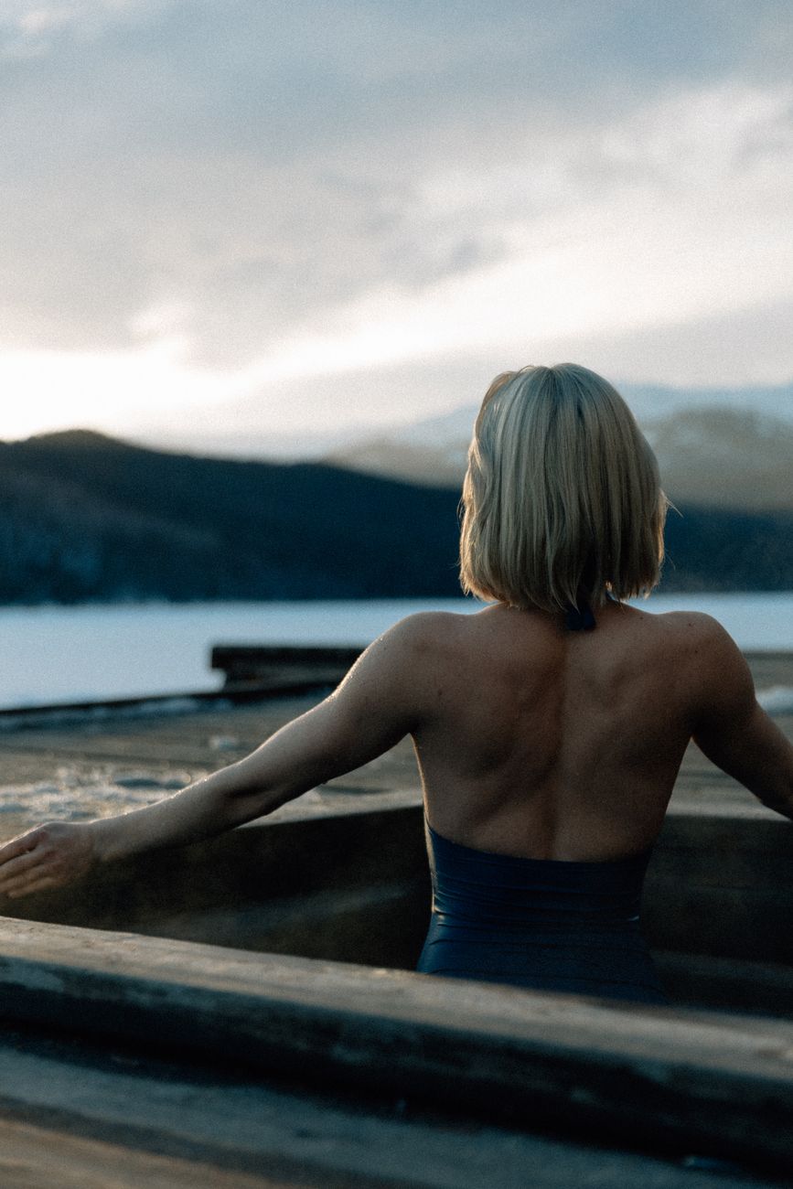 back view of a woman looking at a body of water and mountains