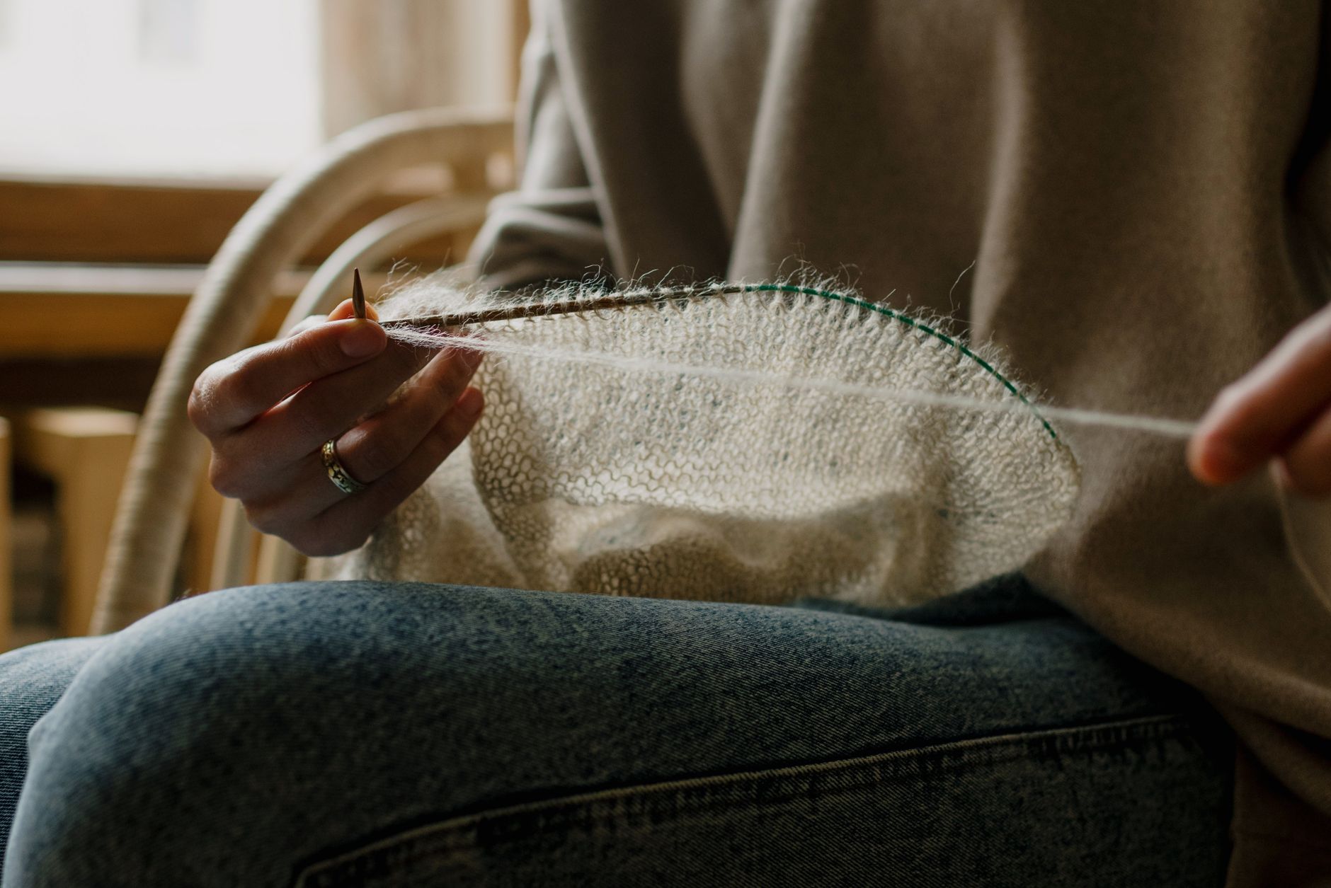 crop artisan pulling thread while knitting clothes at home