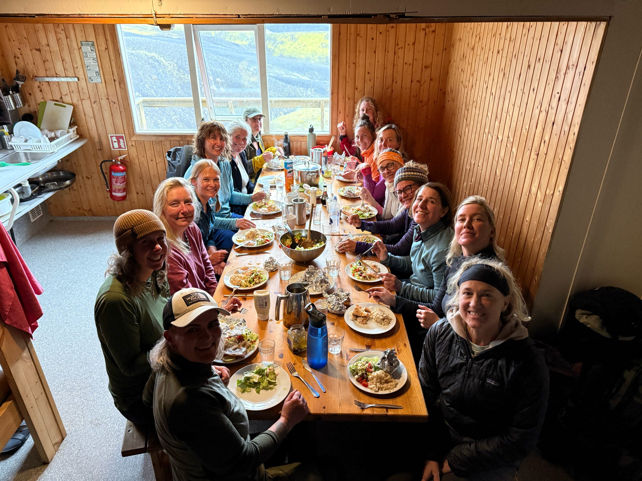 Group sharing dinner at a long table in a wooden hut
