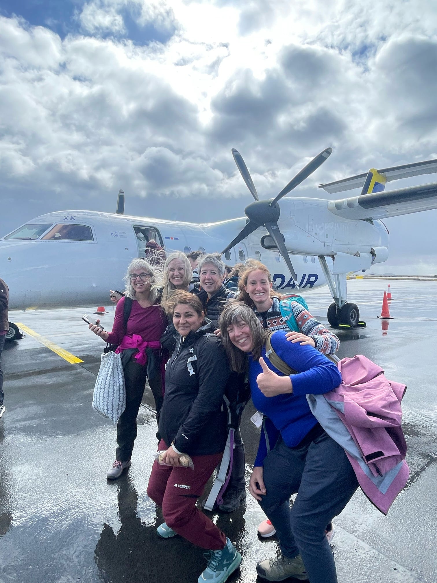 Group of women posing by a small propeller plane