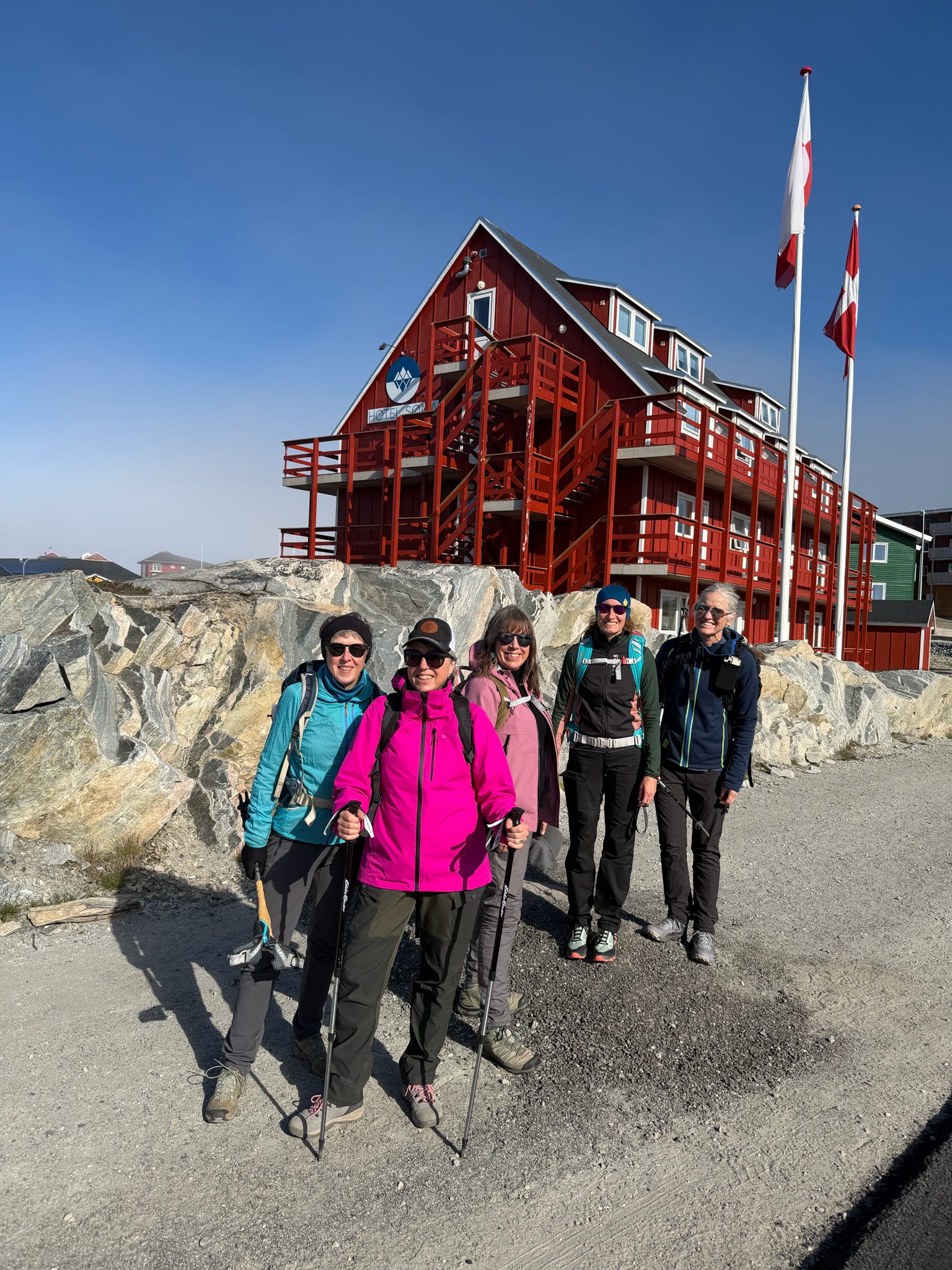 Group of hikers by a red wooden building with flags