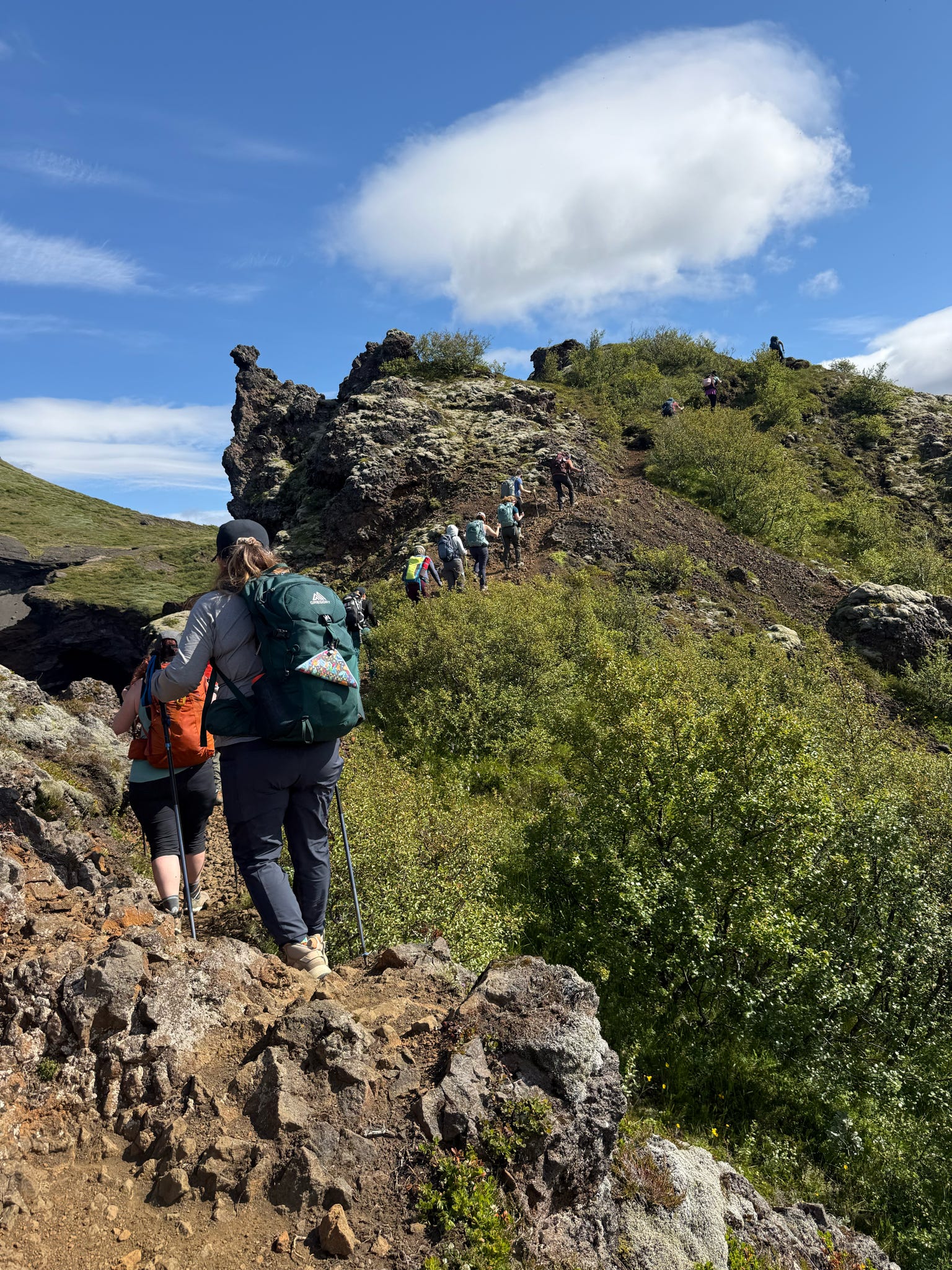 Hikers on a rocky trail under a blue sky
