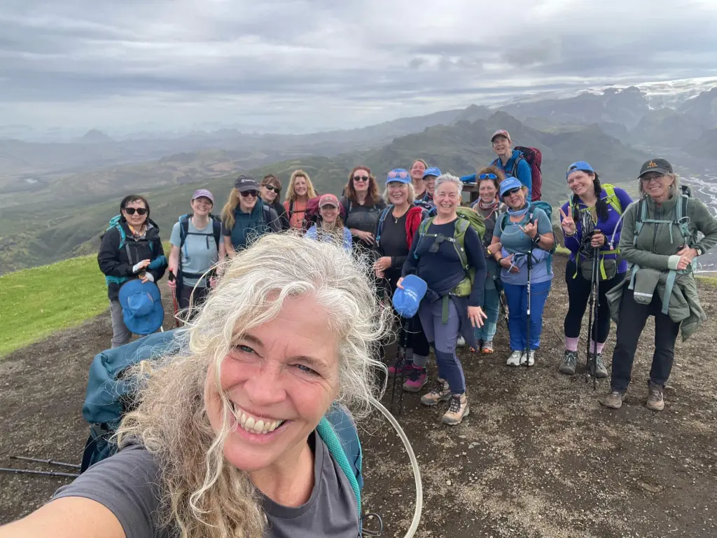 Smiling woman taking a selfie with a group of hikers behind