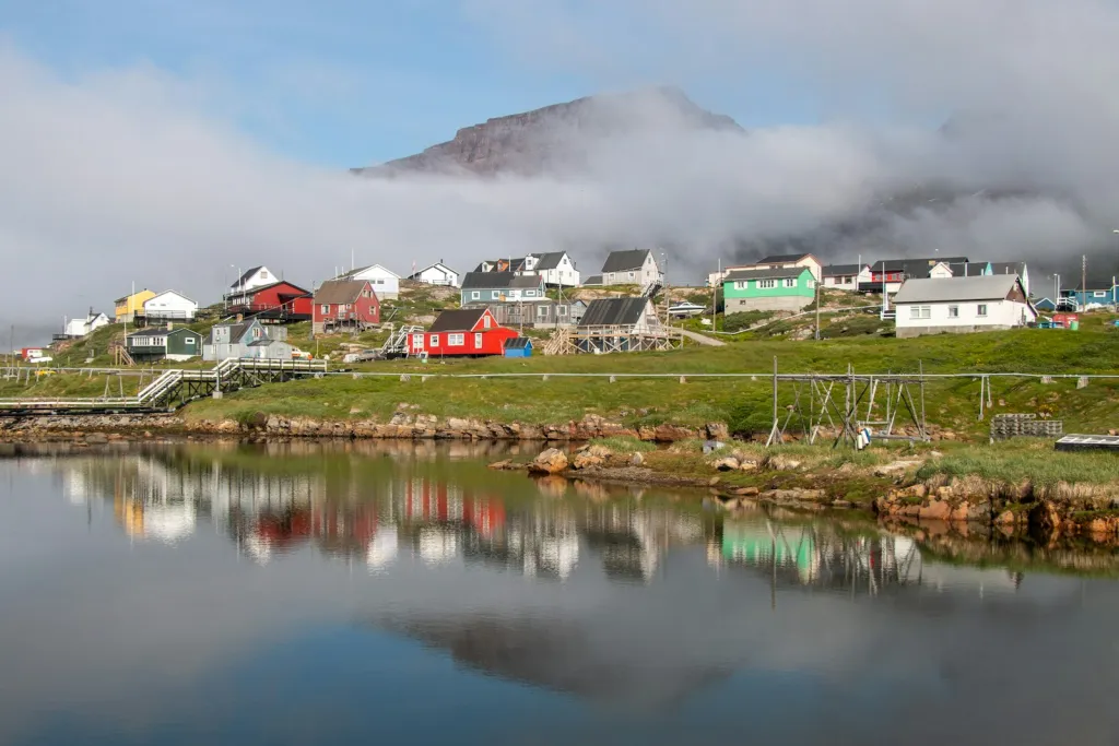 Colorful houses reflected in a lake below a misty mountain