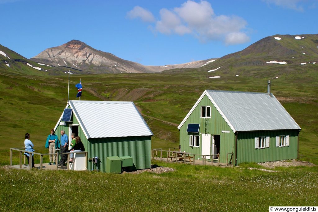 Two green mountain huts in a grassy valley