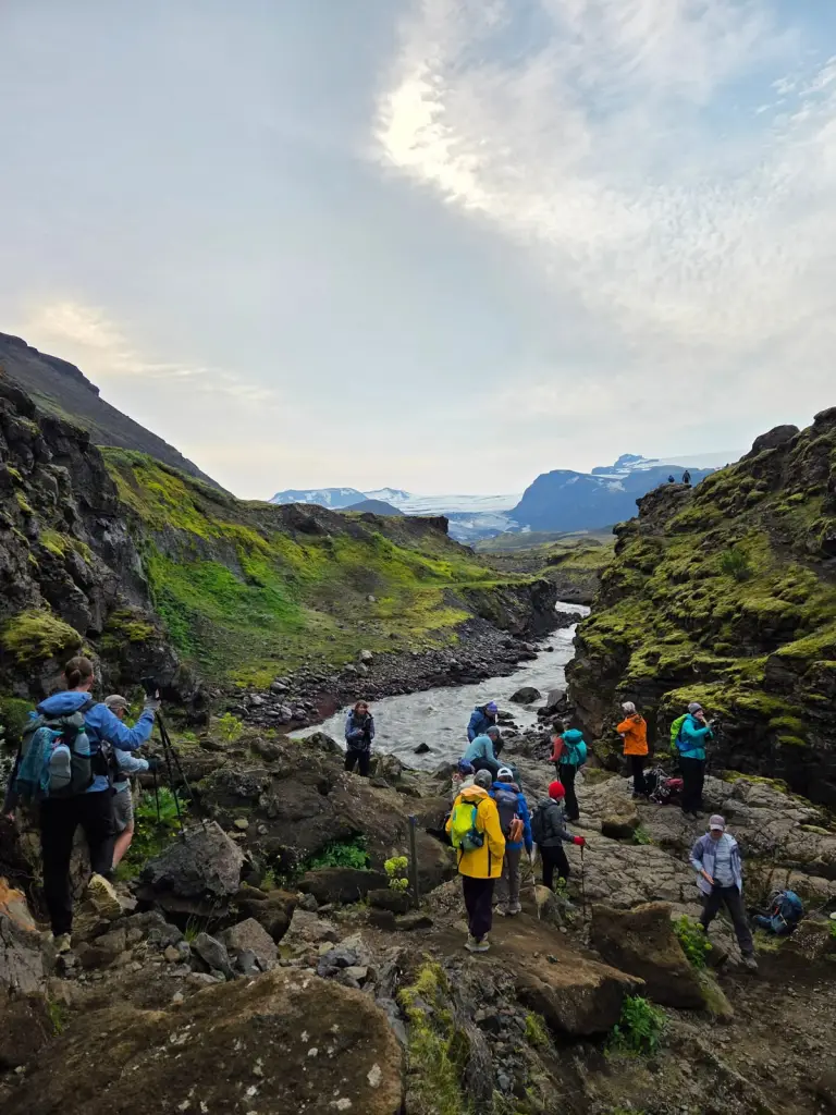 Hikers on a rocky trail beside a mountain river