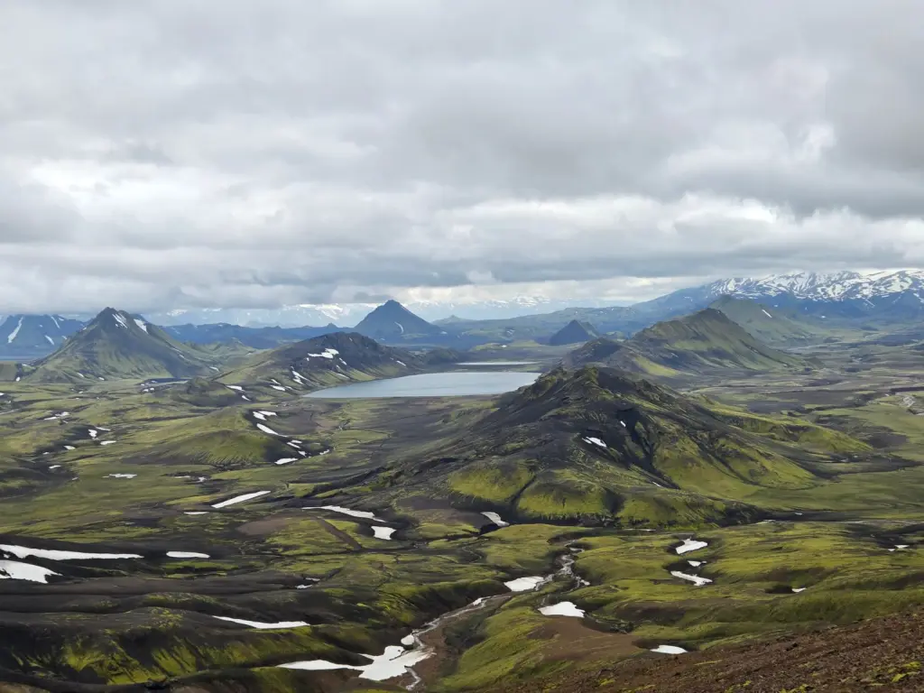 Green highland landscape with a lake and distant mountains