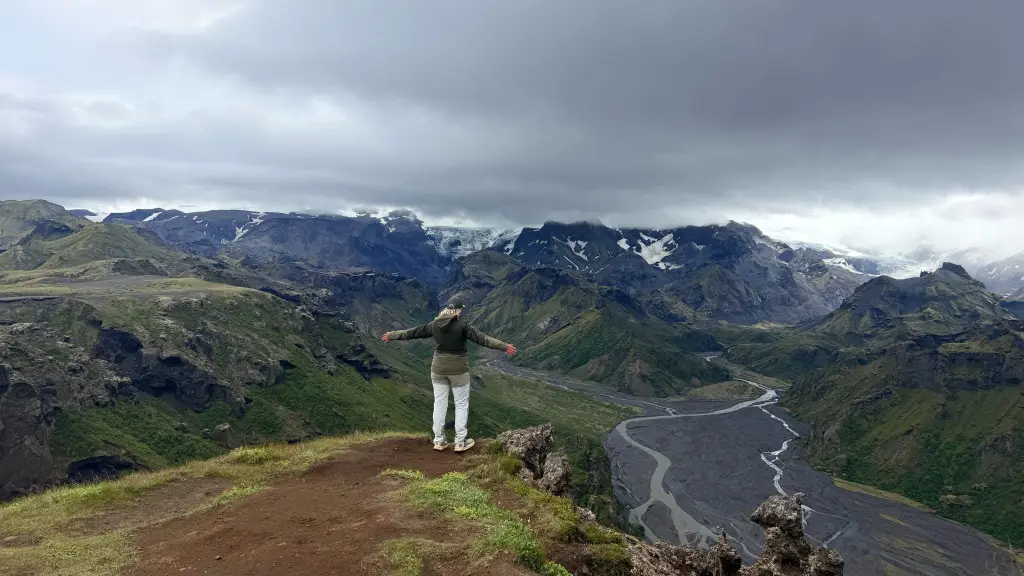 Hiker standing on a viewpoint above a glacial river valley
