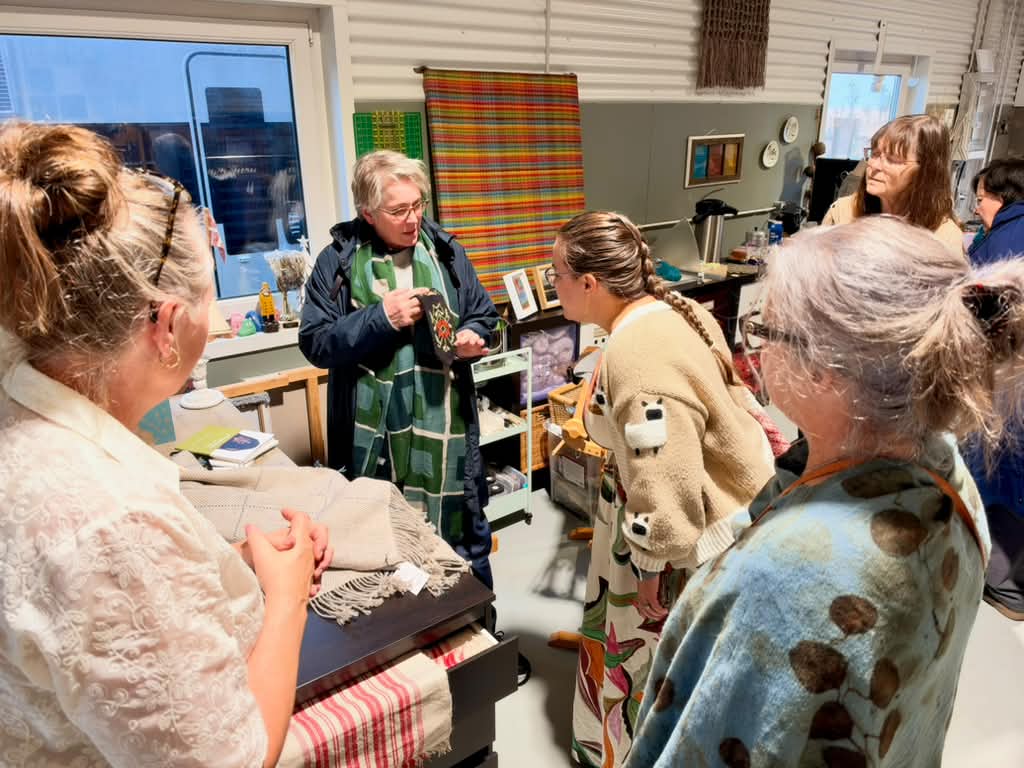 Women looking at handwoven textiles in a craft workshop