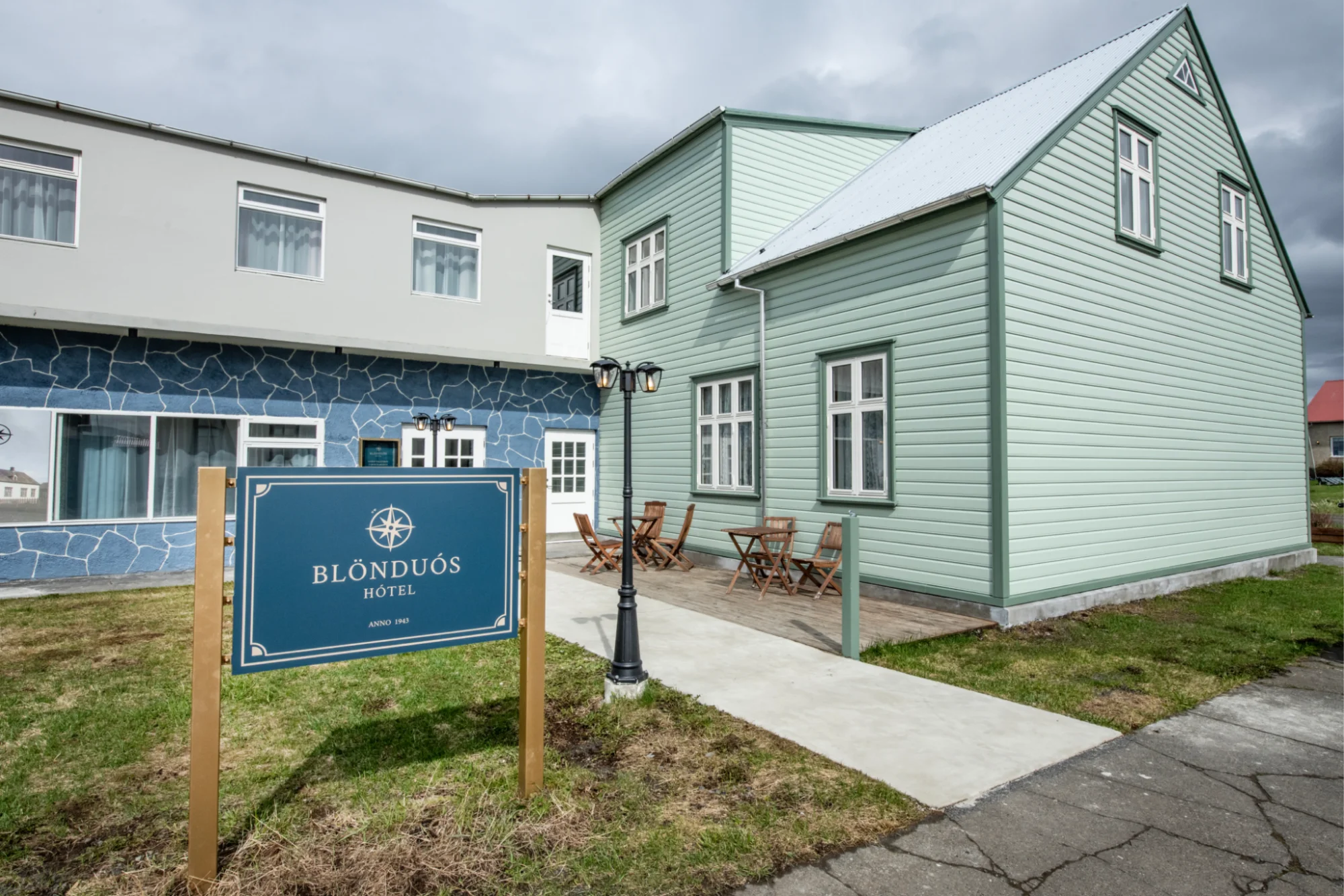Light green wooden hotel building with a sign in front